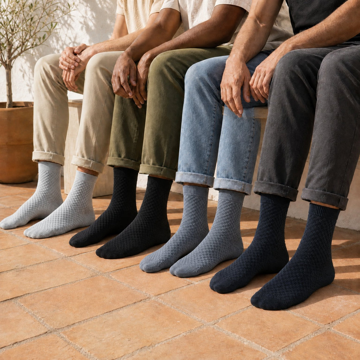 Cuatro personas con calcetines de media caña de bambú Vittorio en gris perla, negro, gris azulado y azul marino
